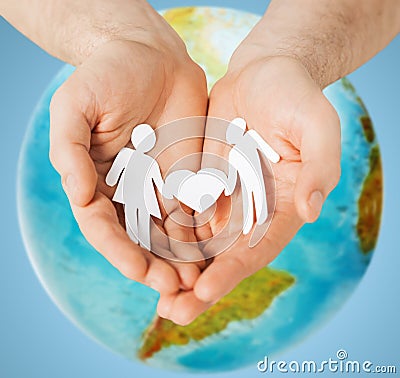 Human hands holding paper couple over earth globe Stock Photo