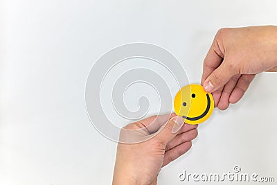 Human hands holding a yellow smiling face on a white background. Be happy and spread happiness concepts Stock Photo