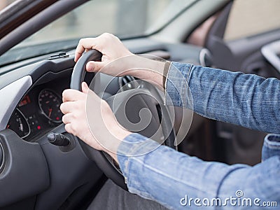 Human hands on steering wheel, inside cab view, close up, selective focus. Ordinary man driving a car. Stock Photo