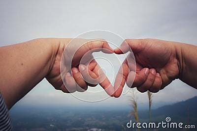 Human hands together in heart shape selectable focus sky background love day concept. Stock Photo