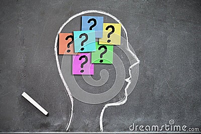 Human head shape on a blackboard with question marks on post-its inside Stock Photo