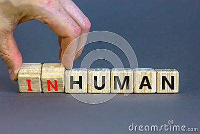 Human or inhuman symbol. Businessman turns wooden cubes and changes the word inhuman to human. Beautiful grey table grey Stock Photo