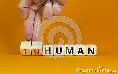 Human or inhuman symbol. Businessman turns wooden cubes and changes the word inhuman to human. Beautiful orange table orange Stock Photo