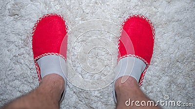 Human,male legs in slippers standing on a white rug,top view,red slippers,home lifestyle. Stock Photo