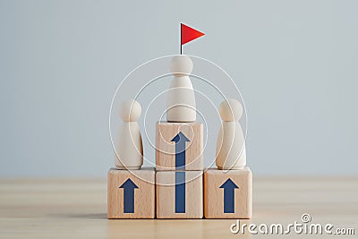 Wooden human on top of wooden block with rise arrow and red flag. Human Resource Development concept. Stock Photo