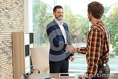 Human resources manager shaking hands with applicant during job interview Stock Photo