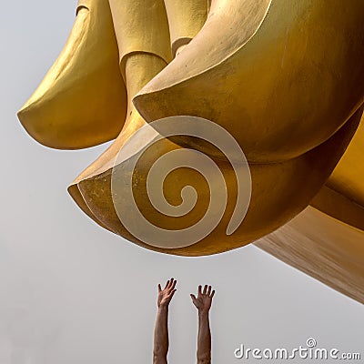 Human`s hands are stretched to a big buddha fingers at Wat muang Ang Thong province. Distance between peoples and gods Stock Photo