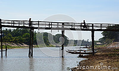 Human silhouettes on wooden bridge. Waw. Bago region. Myanmar Editorial Stock Photo