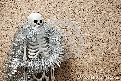 The human skeleton is wrapped with shiny New Year`s decoration on the left of it is the free surface of a beige flower Stock Photo
