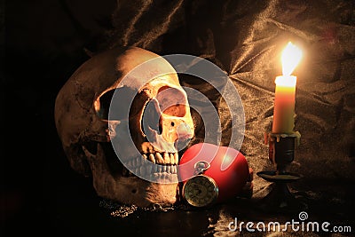 Human skull with vintage pocket clock, red heart and candle light on black fabric background , Love and time concept in still life Stock Photo