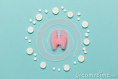 Human thyroid gland and pills on a blue background. Treatment and prevention of the endocrine system. Symptoms of the disease and Stock Photo