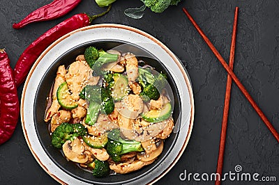 Hunan Chicken in black bowl at dark slate background. Chinese or indo-chinese cuisine takeaway dish Stock Photo