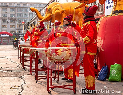 Women in red golden outfits drumming during the ceremonial of the opening of a store in Hunchun city of China, Jilin Editorial Stock Photo