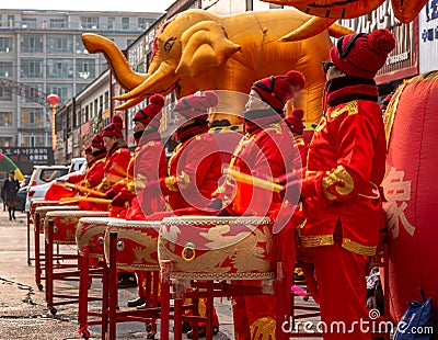 Women in red golden outfits drumming during the ceremonial of the opening of a store in Hunchun city of China, Jilin Editorial Stock Photo