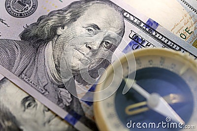 Hundred dollar bills and blurry old compass. Close-up. Sele Stock Photo