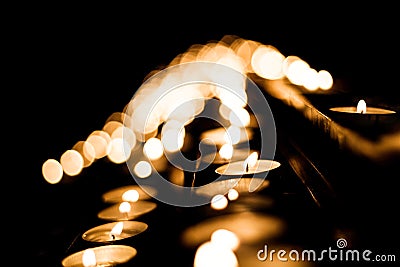 Hundreds of votive candles, focus on one candle close, shallow depth of field, bokeh. Many small tea light candles, fire Stock Photo