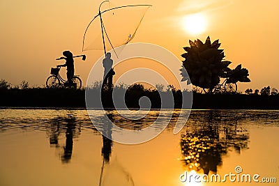 Hung Yen, Vietnam - July 9, 2016: Vietnamese rural countryside sunset scene with silhouette farmers carrying bamboo fish traps hom Editorial Stock Photo