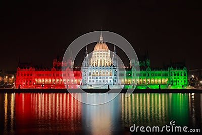 The hungarian Parliament by night lit in national colors In memory of the 1956 war of independence with Danube Stock Photo