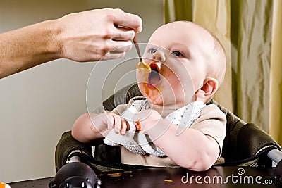 Hungry baby eating solid food from a spoon Stock Photo