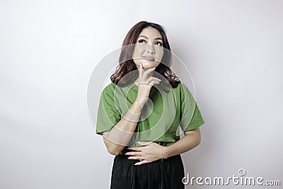 Hungry beautiful Asian woman in green t-shirt holding her stomach think of tasty food isolated over white background Stock Photo