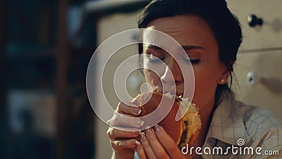 Hungry girl eating burger on floor. Young woman drinking red wine at home. Stock Photo