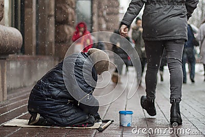Hungry homeless beggar woman beg for money on the urban street in the city from people walking by, social documentary concept Stock Photo