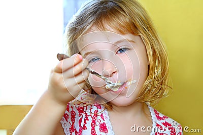 Hungry little blond girl spoon eating ice cream Stock Photo