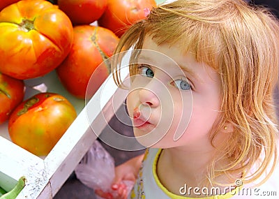 Hungry little girl gesturing in market tomatoes Stock Photo