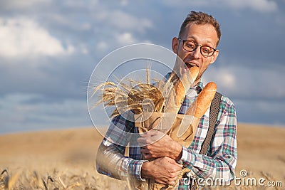 Hungry man bites baguettes in rye field Stock Photo
