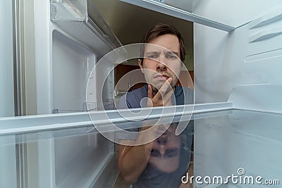 Hungry man is looking for food in empty fridge Stock Photo