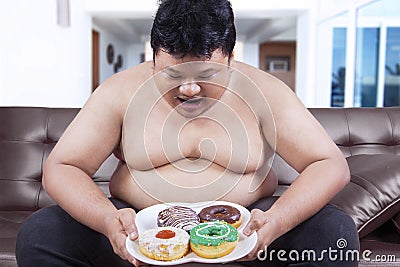 Hungry overweight man holding donuts Stock Photo
