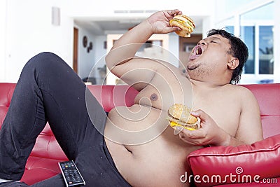 Hungry overweight person eats burger at home Stock Photo