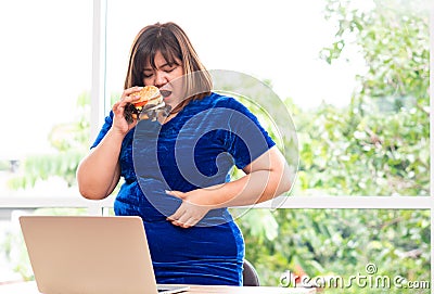 Hungry overweight woman holding hamburger, During work from home, gain weight problem. Concept of binge eating disorder BED Stock Photo