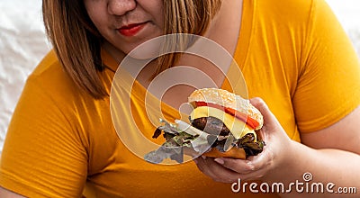 Hungry overweight young asian woman holding hamburger, Her hungry all time and overeat, gluttony and binge eating. Her lifestyle Stock Photo