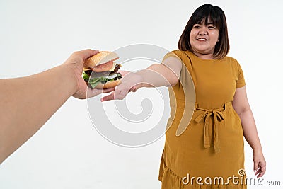 Hungry overweight young Asian woman holding hamburger on isolated background, Her hungry all time and overeat, gluttony and binge Stock Photo