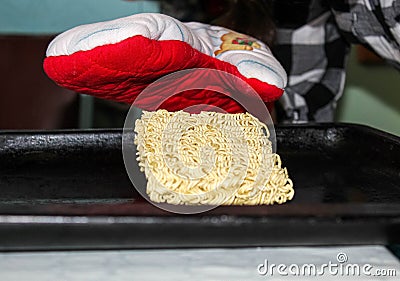 A hungry person about to cook instant noodles on a baking sheet in the oven Stock Photo