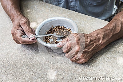 Hungry. Poor old man& x27;s hands an bowl of porridge . Selective focus. Poverty in retirement Stock Photo