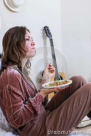 Hungry woman eating pasta spaghetti at serving table with wrapped gift box enjoy holiday celebrating Stock Photo