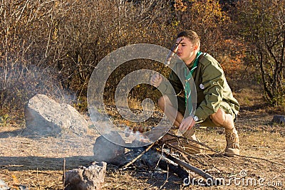 Hungry young scout cooking sausages Stock Photo