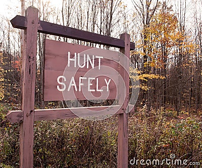 A `HUNT SAFELY` sign on in the fall woods Stock Photo