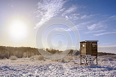 Hunter high seat in a snow covered winter landscape against a blue sky with a warm sun, copy space Stock Photo