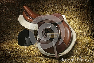 Hunter/jumper saddle and hunt cap on bales of straw Stock Photo