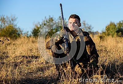 Hunter satisfied with catch relaxing. Rest for real man concept. Hunter with rifle relaxing in nature environment. Tired Stock Photo