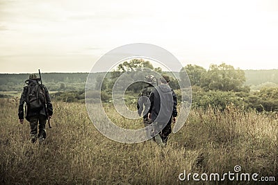 Hunters going on rural field at sunrise during hunting season Stock Photo