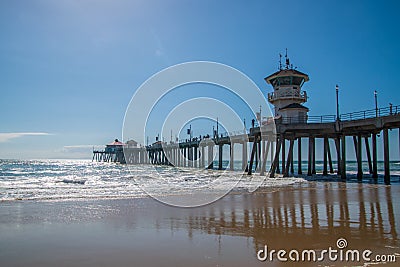 The Huntington Beach Pier as seen on a sunny day from a beach view looking up showing the concrete pillars on the underside of the Editorial Stock Photo