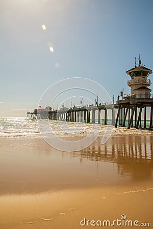 The Huntington Beach Pier as seen on a sunny day from a beach view looking up showing the concrete pillars on the underside of the Editorial Stock Photo
