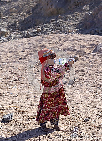 Bedouin children entertain tourists. Kids of the Sahara desert. An aboriginal child with a bottle of water Editorial Stock Photo