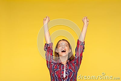 Hurray, victory! Portrait of delighted girl in checkered shirt yelling for happiness, enjoying life, rejoicing success with arms Stock Photo