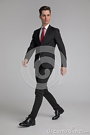 Hurried man in black suit walking while looking away Stock Photo