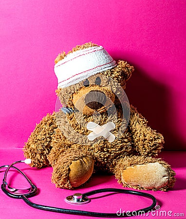 Hurt child`s teddy bear with stomach and head bandage Stock Photo